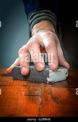 Tuttofare lavora con la carta vetrata su una tavola di legno. Foto Stock