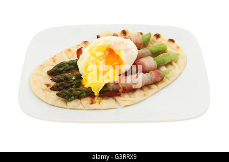 Pancetta avvolto asparagi con un naso che cola tuorlo d'uovo in camicia e flatbread su una piastra isolata contro bianco Foto Stock