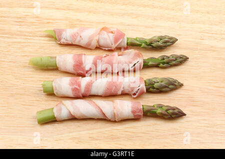 Gli asparagi spears avvolto con pancetta su un tagliere di legno Foto Stock