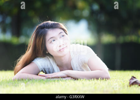 Asia bella giovane donna sdraiata su erba verde in vacanza Foto Stock