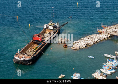 Un rimorchiatore-gru montata lavorando su un masso molo nel porto di Marina Grande - Sorrento, vicino a Napoli, Italia Foto Stock