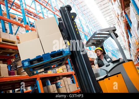 Lavoratore di magazzino utilizzando un carrello elevatore Foto Stock