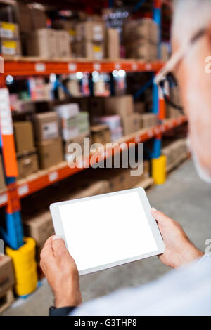 Vista posteriore del warehouse manager cercando il proprio computer tablet Foto Stock