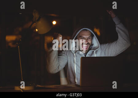 Uomo felice usando un computer portatile durante la notte Foto Stock