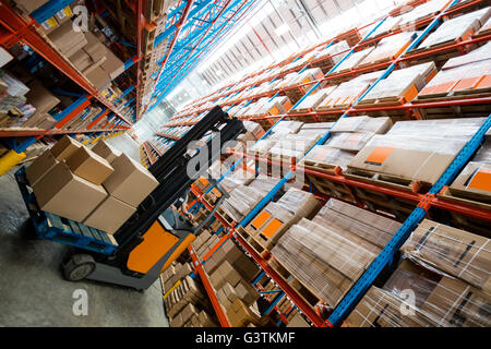 Lavoratore di magazzino utilizzando un carrello elevatore Foto Stock