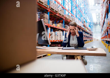 Sottolineato imprenditrice seduta sulla sua scrivania Foto Stock