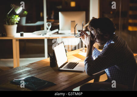 Imprenditore oberato di lavoro utilizzando computer portatile durante la notte Foto Stock
