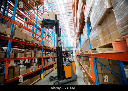 Lavoratore di magazzino utilizzando un carrello elevatore Foto Stock