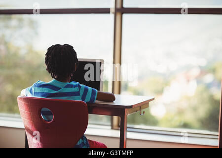 Scolaro seduti su una sedia e utilizzando laptop a scuola Foto Stock