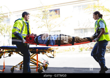 Trasporto Ambulancemen uomo ferito su una barella Foto Stock