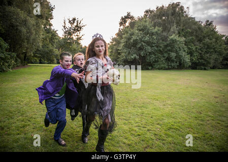 Bambini inseguire una ragazza vestita come uno zombie prom regina per la notte di Halloween. Foto Stock