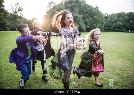Bambini inseguire una ragazza vestita come uno zombie prom regina per la notte di Halloween. Foto Stock