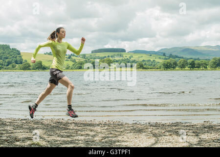 Una ragazza che corre sulla riva accanto a Bala Lake in Galles. Foto Stock