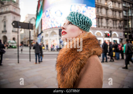 Un elegante giovane donna vestita in stile anni trenta capi di abbigliamento a piedi circa a Piccadilly Circus. Foto Stock