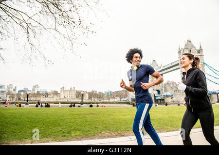 Una giovane coppia jogging insieme passato il Tower Bridge di Londra. Foto Stock