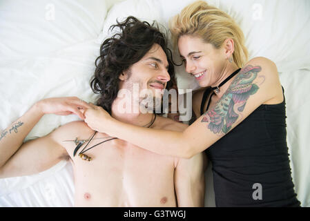 Un giovane tatuato giovane cuddling su un letto. Foto Stock