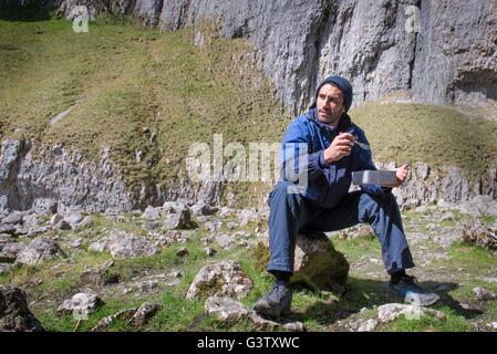 Un alpinista seduti a mangiare cibo in terreni accidentati. Foto Stock