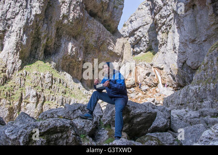 Un alpinista seduti a mangiare cibo in terreni accidentati. Foto Stock