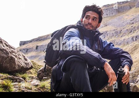 Un alpinista seduto in un terreno accidentato. Foto Stock