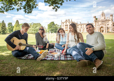 Gli amici sorseggiando un picnic sulle rive del fiume Cam in Cambridge. Foto Stock