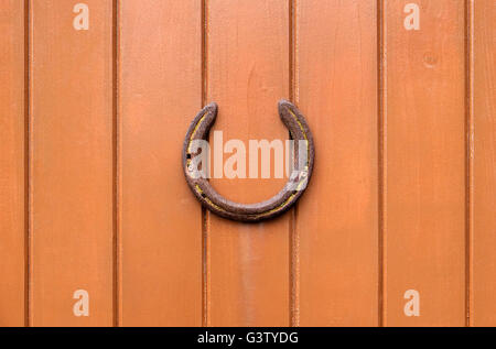 Ferro di cavallo vecchio su marrone dipinto in legno parete in legno Foto Stock