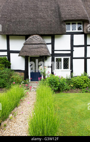 Con il tetto di paglia in bianco e nero con cornice in legno cottage e giardino. Ashton sotto la collina, Wychavon district, Worcestershire, Regno Unito Foto Stock