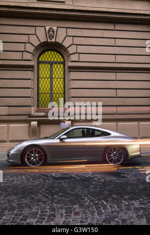 Porsche 911 Carrera S parcheggiata su strada con striature chiare dal passaggio di veicoli contro la classica architettura in stile con green wi Foto Stock