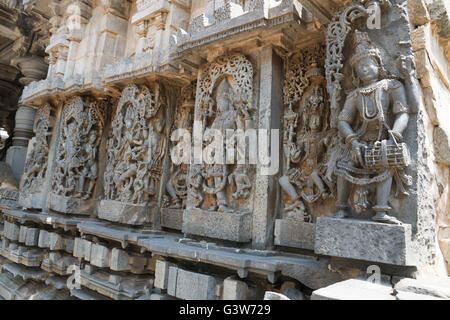 Ornati pannello parete rilievi raffiguranti divinità Indù, lato ovest, hoysaleshwara tempio, halebidu, Karnataka, India. Foto Stock