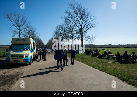 La gente che ottiene di gelato, camminando per un sentiero e seduta a banchi di picnic. Foto Stock