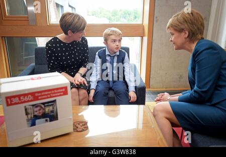 La distrofia muscolare sofferente Michael Young di nove anni, con sua mamma Michelle (sinistra), presenta una petizione al Primo Ministro Nicola Storione presso il parlamento scozzese di Edimburgo. Foto Stock