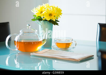 Tè con teiera e bouquet di margherite giallo sul tavolo Foto Stock