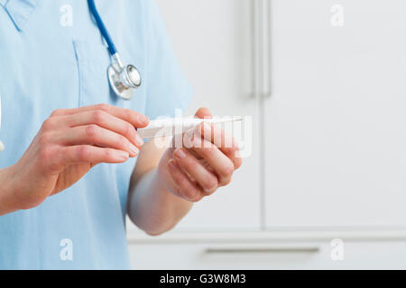 Femmina azienda infermiere termometro Foto Stock