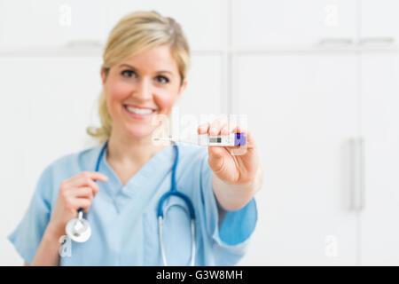 Femmina azienda infermiere termometro Foto Stock