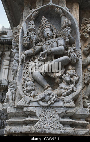 Ornati pannello parete bassorilievi raffiguranti Shiva ballando sulla testa di Gajasura, tempio Kedareshwara, Halebidu, Karnataka, India. Foto Stock