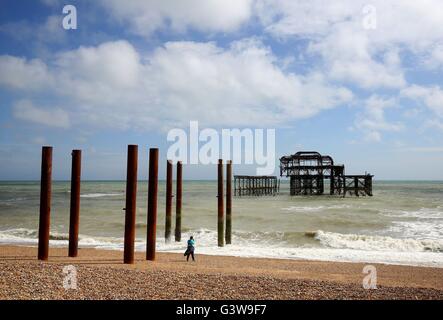 Una signora prende un'immagine dell'ex Molo Ovest di Brighton, East Sussex durante il pomeriggio di sole. Foto Stock