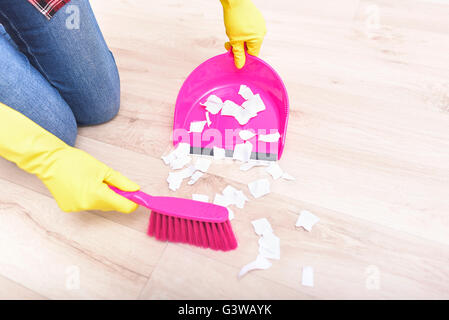 Sweep finemente pezzi strappati di carta sul pavimento. Foto Stock