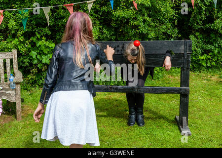 Una ragazza getta acqua bombe al suo amico che è in stock, la Fiera medievale di Abinger, Surrey, Regno Unito Foto Stock