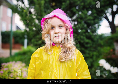 Foto esterni della bimba bionda in impermeabile giallo Foto Stock