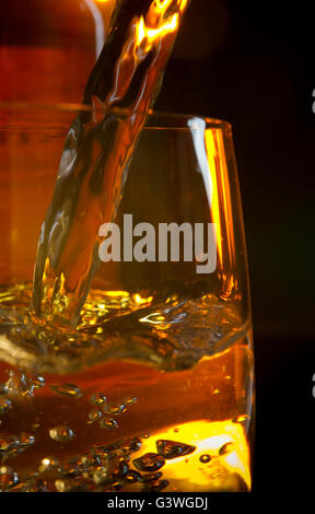 Il whiskey è versata in un elegante bicchiere Foto Stock