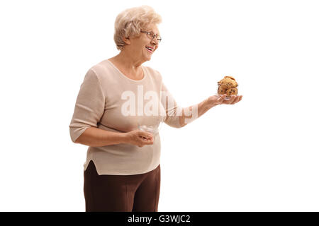 Senior donna tenendo un vaso di biscotti e offrendo loro a qualcuno isolato su sfondo bianco Foto Stock