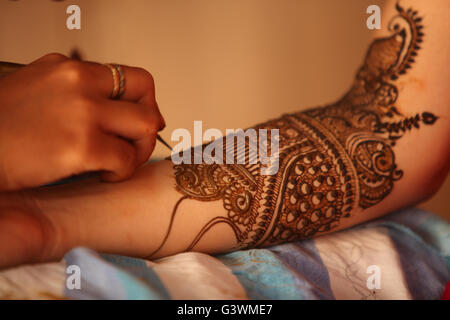 Un artista rendendo il design tradizionale con bellissimi modelli di henna mehendi o sulle mani di un indiano sposa. Foto Stock