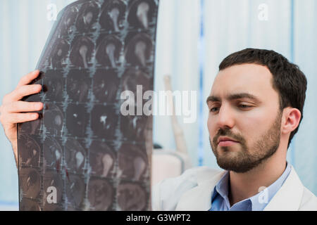 Medico visualizzazione scansioni MRI presso il suo ufficio Foto Stock