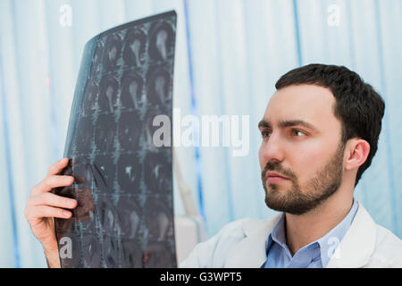 Medico visualizzazione scansioni MRI presso il suo ufficio Foto Stock