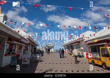 Le bandiere e pavese di contrasto contro un cielo blu all'ingresso del Grand Pier sul lungomare di Weston-Super-Mare. Foto Stock