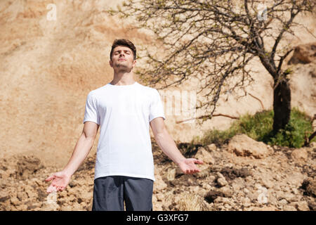 Rilassata bel giovane uomo in piedi e meditando all'aperto Foto Stock