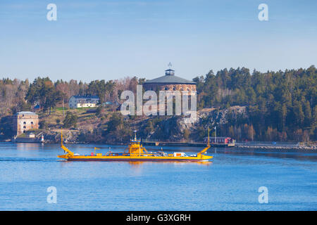 Piccolo giallo traghetto roll on-roll off va vicino a Oscar medievale Fredriksborgs fortificazione. I punti di riferimento di Vaxholm, arcipelago di Stoccolma, Swed Foto Stock