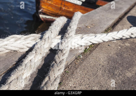 Funi nautico utilizzato per le operazioni di ormeggio giaceva sul molo, closeup foto con messa a fuoco selettiva Foto Stock