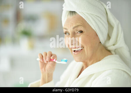 Donna anziana spazzolare i suoi denti Foto Stock