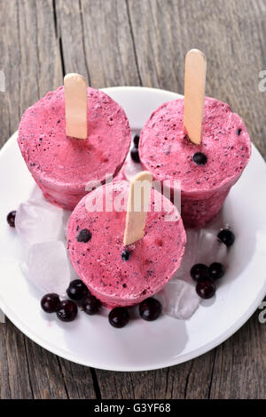 Mirtillo ribes nero popsicles realizzati in tazze sullo sfondo di legno Foto Stock