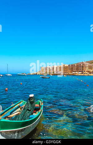 Barca da pesca ormeggiata nella baia di Marsalforn e panorama della più popolare e più grande località estiva di Gozo - Marsalforn, Gozo, Malta Foto Stock